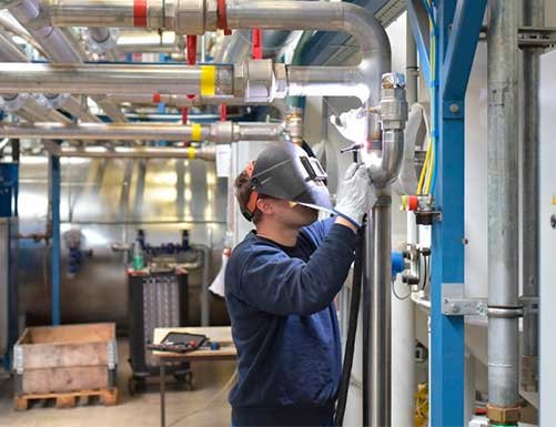 Mantenimiento industrial en una fábrica con un trabajador al lado del sistema de tubería