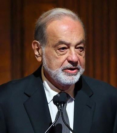 Ingeniero mexicano Carlos Slim Helú dando un discurso en un curul junto a una bandera de México - ingenieros civiles