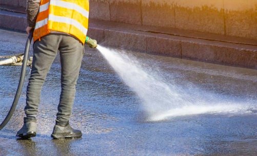 Constructor utilizando agua para llevar a cabo el curado del hormigón de una losa maciza