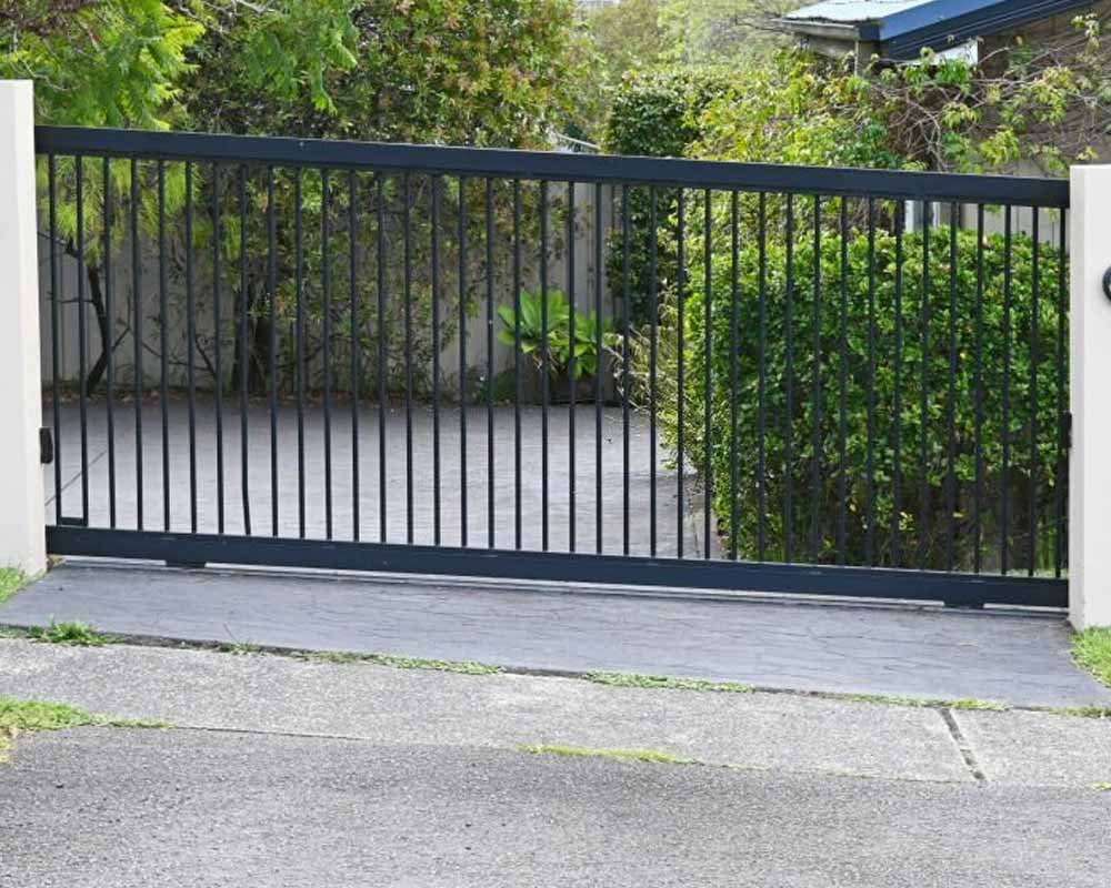 Portón corredizo de estilo moderno de color negro en la entrada de una casa