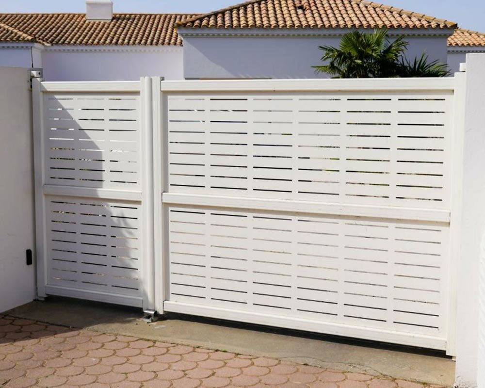 Portón de herrería de color blanco en la entrada de una casa de gran tamaño