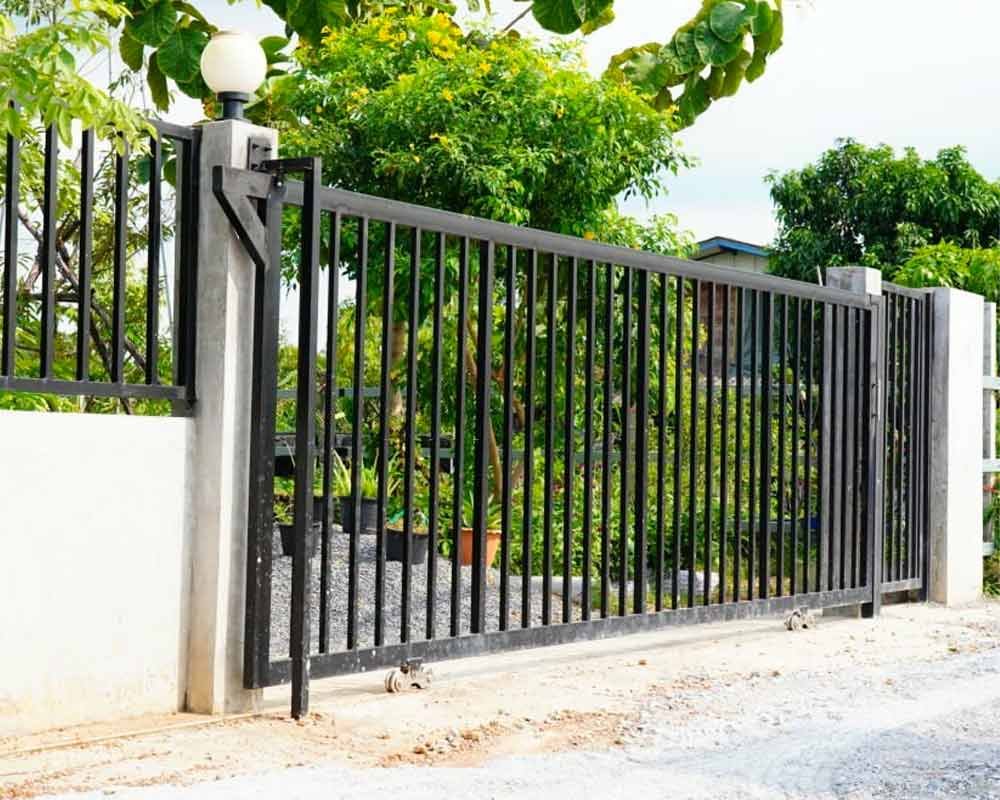 Portón de herrería elaborada con PTR de color negro colocado en la entrada de una casa