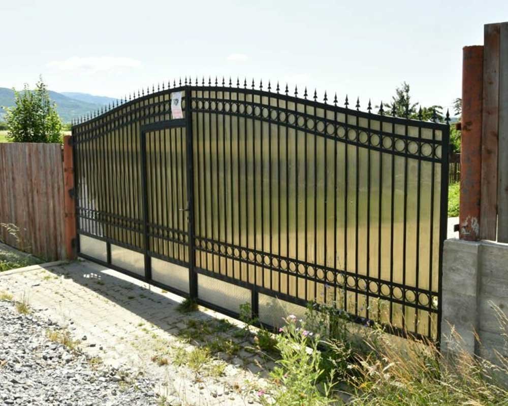 Portón de herrería elaborado con perfiles de acero y lámina de policarbonato colocado en la entrada de un rancho