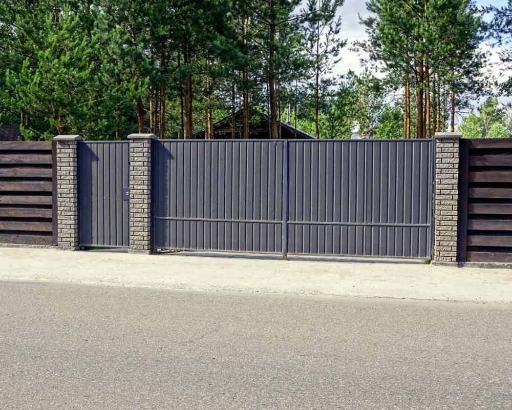 Portón de lámina tipo tablero en la entrada de una casa de campo