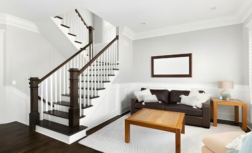 Escalera con barandal de madera con pasamanos café y balaustres de color blanco dentro de una casa