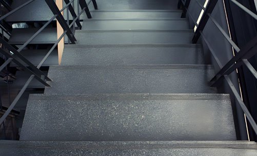 Vista superior de una escalera recta de concreto con un barandal hecho de perfiles de acero