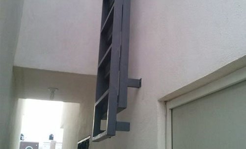 Escaleras marinas plegables instaladas en muro cercano al acceso de un inmueble