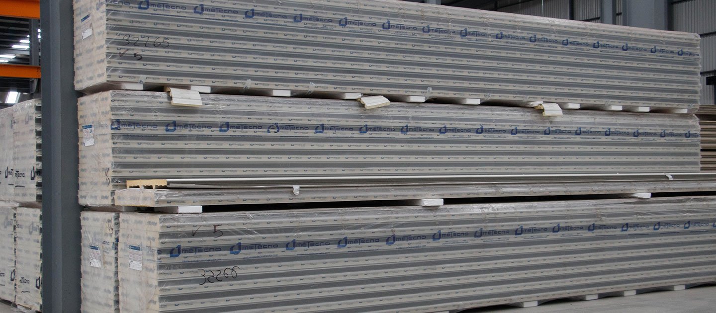 Paquetes apilados de paneles Metecno almacenados en una bodega